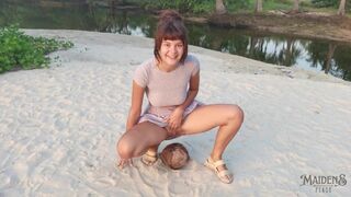 A shy girl squirts a small trickle of pee on a coconut